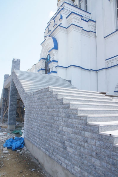 Рабочие ведут наружную отделку лестниц декоративным камнем