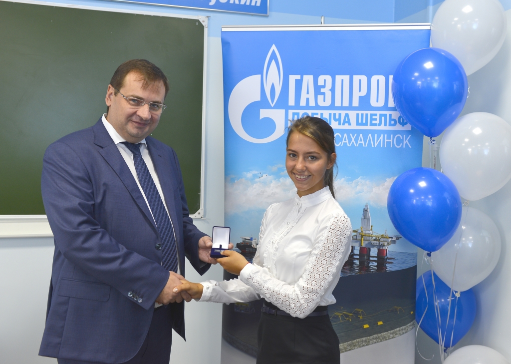 Владимир Кроха вручает ученице первого на Сахалине "Газпром-класс" памятный значок