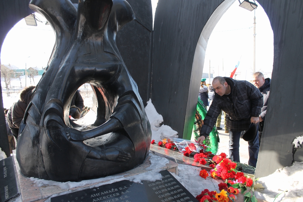 Люди возлагают цветы на памятник